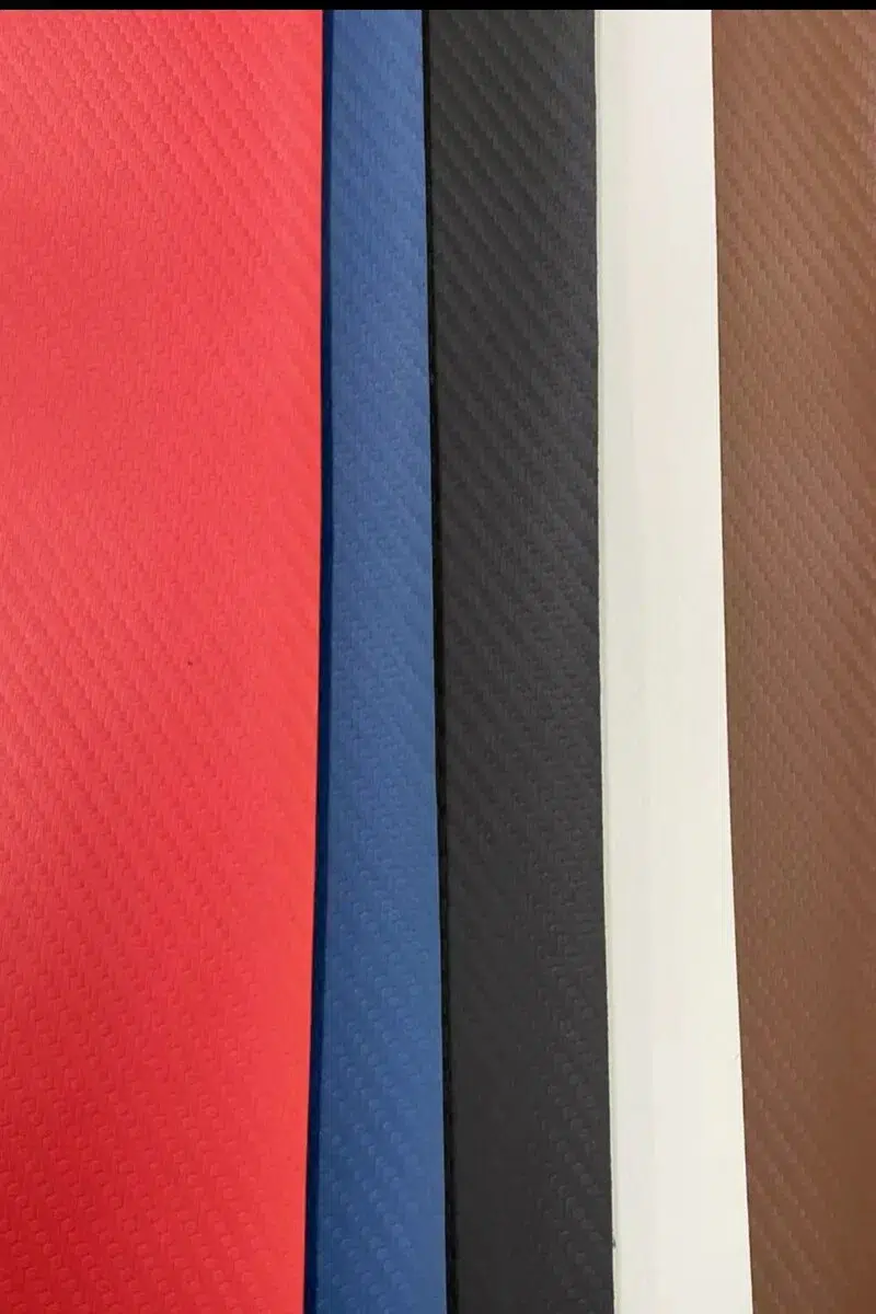 Carbon fiber vinyl upholstery texture from Parma Mer collection showing diagonal weave emboss in multiple colors with soft-touch faux leather surface