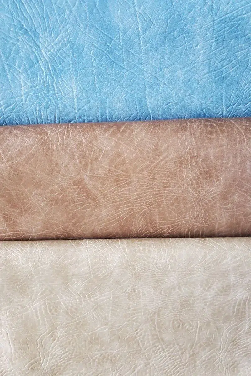 Distressed leather King Ranch upholstery vinyl in light blue, light tobacco brown, and cream color textures