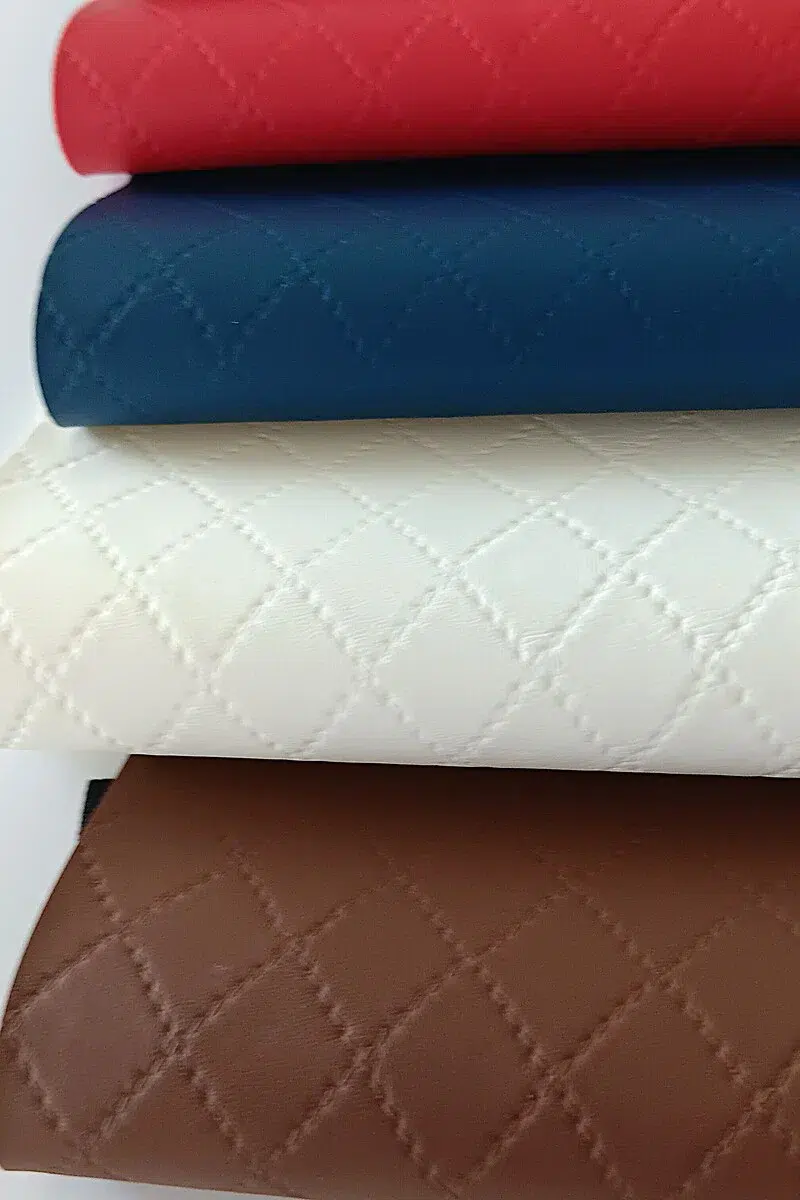 Diamond quilted embossed vinyl texture in black, white, red, blue, and taupe for marine, automotive, and upholstery applications by Joya Mer
